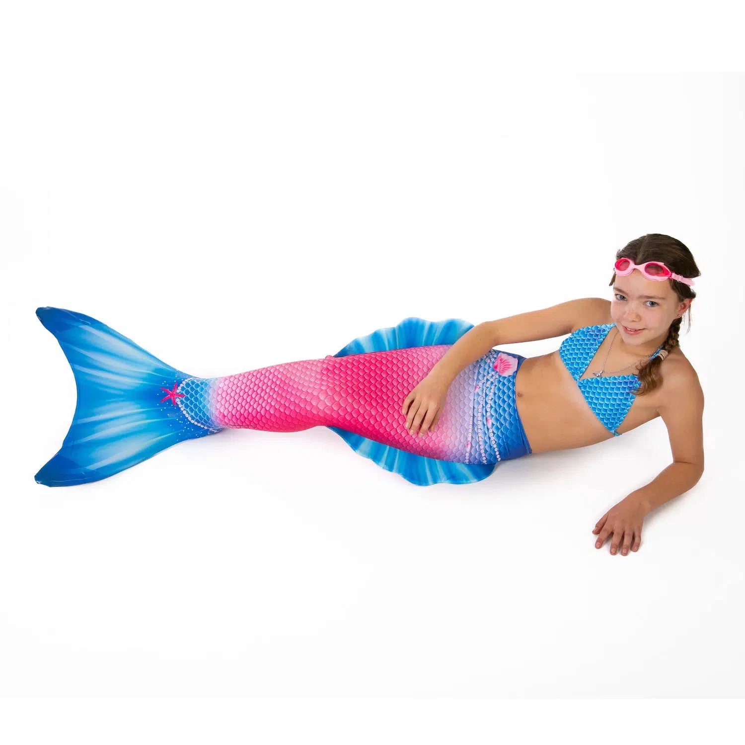 Girl with Ocean Queens Jewel mermaid tail set on. Pink swimming goggles on head| studio photography