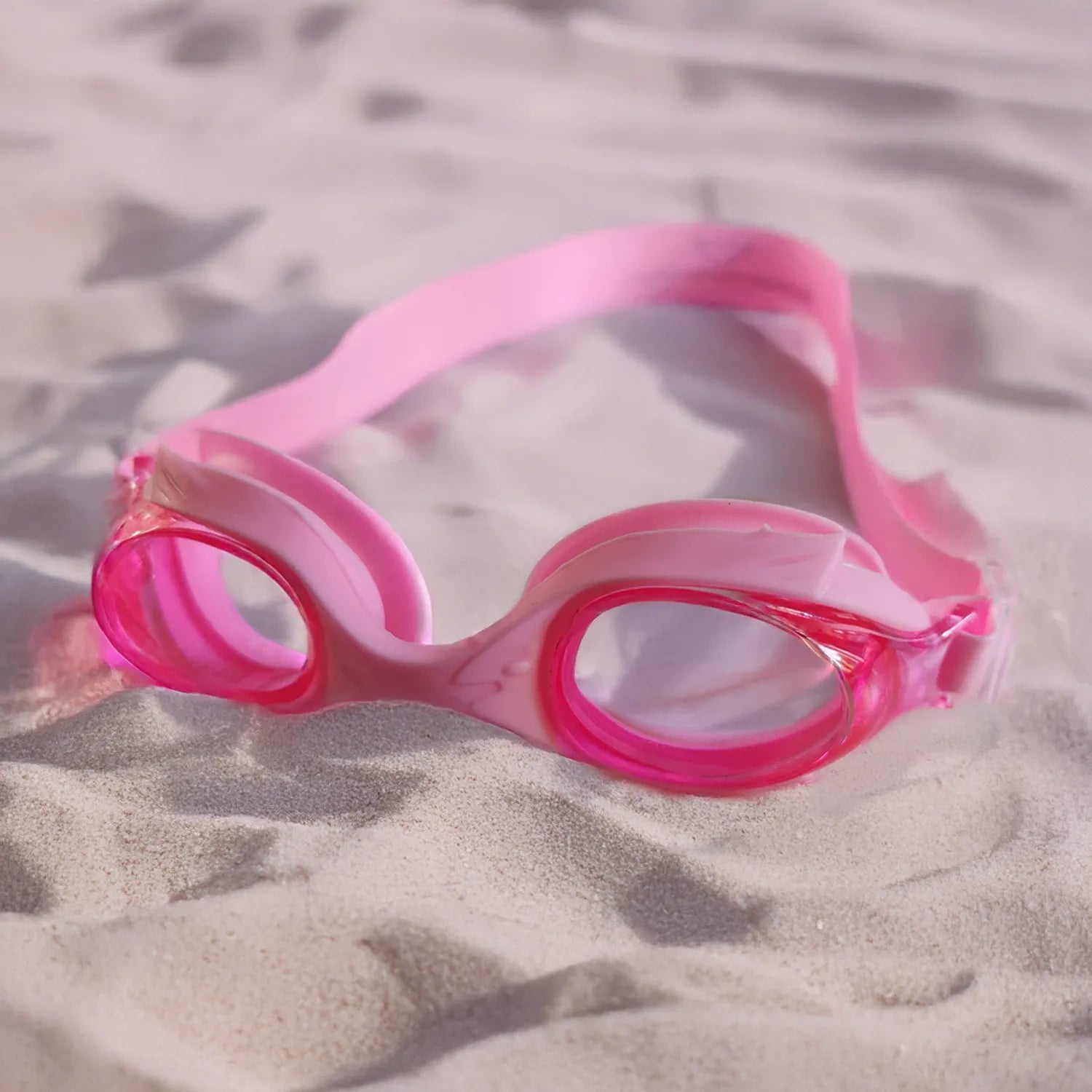Stylish pink goggles for kids on soft sand
